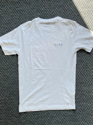 Handbroderad vit t-shirt från Denim Project - Vit t-shirt från Denim Project med handbroderad text 'FIL 4:13' på bröstet. 