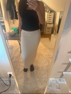 Beige lång tight kjol - Säljer en beige långkjol med tight passform och medel hög midja. Kjolen är enkel och stilren, perfekt att matcha med crop tops eller stickade tröjor. Materialet ser ut att vara stretchigt och mjukt för en bekväm känsla. Endast använd 1-2 gånger. Så den är i ett jätte bra skick.