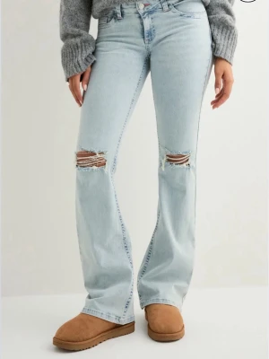 Ljusblå Nelly jeans  - Säljer nu mina bootcut jeans med slitna knän och broderade detaljer på bakfickorna. Jeansen har låg midja och klassisk femficksdesign. I fint skick, säljer då de inte kommer till användning. 