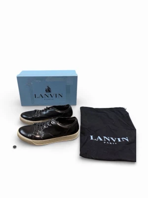 Svarta Lanvin sneakers i läder - Snygga svarta sneakers från Lanvin i blankt läder med vita sulor och klassisk snörning. Skorna har en stilren design och kommer med originalkartong och dustbag. Perfekta för dig som gillar exklusiva och tidlösa sneakers.