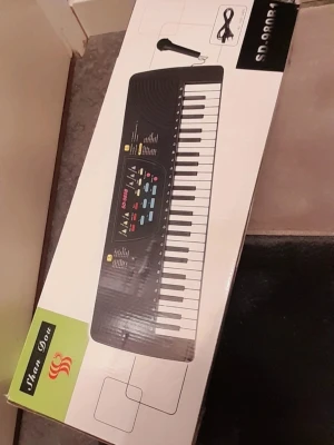 Shan Dou elektroniskt keyboard - Säljer ett elektroniskt keyboard från Shan Dou, modell SD-3000B. Tangentbordet har svart och vit design med flera funktionsknappar i olika färger. Medföljer mikrofon och strömkabel. Perfekt för dig som vill börja spela eller experimentera med musik.