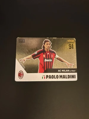 Signerat fotbollskort Paolo Maldini - Unikt samlarkort från 2018 med Paolo Maldini i AC Milan-tröja. Kortet har guldfärgad baksida, spelarstatistik och signaturtryck. Perfekt för dig som gillar fotboll och samlar på legender. Kortet har rating 91 och visar Maldini i rödsvart matchtröja. Kortet har Maldinis autograf på i sin Prime.