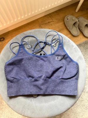 Blå seamless sport-bh från ICANIWILL - Snygg blå sport-bh från ICANIWILL med tunna korsade axelband och seamless design. Bh:n har brottarrygg och ribbad kant nedtill för extra stöd. Materialet är stretchigt och andas, perfekt för träning eller vardag.