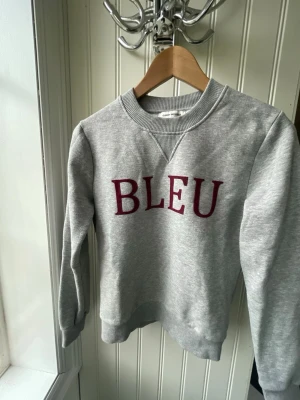 Grå sweatshirt BLEU Carin Wester - Snygg grå sweatshirt från Carin Wester med vinröd text 'BLEU' framtill. Tröjan har rund halsringning, ribbade muddar och är tillverkad i mjukt sweatshirtmaterial. Jättefin😍😍