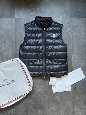 Moncler gui väst  - Tjena, säljer nu denna riktigt snygga och populära Moncler gui västen, den är i nyskick, inga skador, 2022 model, påse, lappar och extraknappar ingår, storlek 2 passar S/M, hör av er vid frågor och funderingar🙌🤝 
