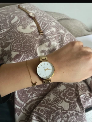 Mockberg guld klocka med meshband - Stilren klocka från Mockberg i guld med vitt ur och minimalistisk design. Klockan har ett tunt meshband i metall och en rund urtavla med guldfärgade visare och markeringar. Perfekt accessoar för dig som gillar klassisk och elegant stil.💞