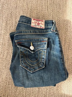 True Religion jeans  - Säljer ett par trendiga blåa jeans från True Religion med snygga detaljer på bakfickan. Jeansen har låg midja och klassisk femficksdesign. Sista bilden är inte min💗