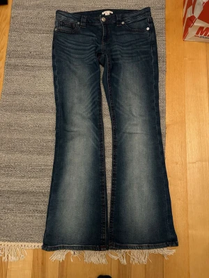 Bootcut jeans från Gina Tricot M 14+ - Mörkblå bootcut jeans sopar golvet med sin snygga tvätt och lätt slitna look. Klassisk femficksmodell a la Gina Tricot, med knapp och dragkedja framtill. Jeansen har en skön stretchig denimkänsla och markerade sömmar.
