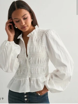 Vit blus  - Säljer denna blus från Nelly helt ny med prislapp på, är mer som en 36 än 34. Skriv privat för bilder💕