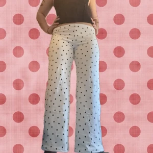 Lågmidjade mjukisar med svarta prickar - Snygga lågmidjade byxor med svarta prickar och utsvängda ben. Låg midja och stretchigt material som sitter bekvämt. Perfekta för dig som vill sticka ut med ett lekfullt mönster. Passar till crop tops eller oversized tröjor. Sydd av mig! Sitter såhär på mig med storlek M.