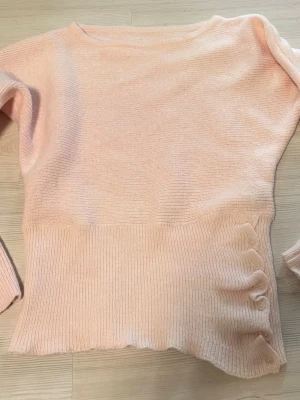 Ljusrosa stickad tröja med justerbara knappar Shein - Supersöt ljusrosa stickad tröja med ribbad nederdel som ger en unik look och dekorativa knappar på sidan som man kan öppna och justera. Perfekt för dig som gillar en feminin och enkel stil.