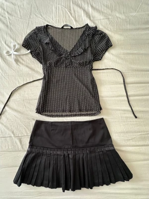 Svart plisserad kortkjol - Snygg svart plisserad kortkjol med klassisk tennisvibe. Kjolen har en hög midja och är gjord i ett mjukt tyg som känns bekvämt. Perfekt att styla med crop tops eller oversized tröjor för en trendig look.