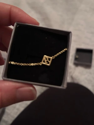 Guldigt armband med bokstav R  - Snyggt och stilrent armband i guldplaterad med en tunn kedja och en fyrkantig berlock med bokstaven R  i mitten. Perfekt accessoar för dig som vill ha något personligt och trendigt. Levereras i en liten ask. 