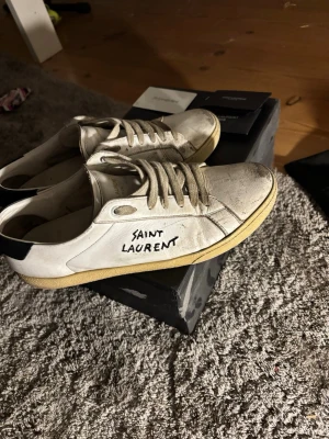 Saint Laurent skor.  - Vita sneakers från Saint Laurent med handskriven logga på sidan. Nypris är ca 5-6 tusen säljer för endast 1000 kronor. Det finns tecken på användning så den behöver lite kärlek. Tveka inte på att höra av er. Mvh Resellclts 