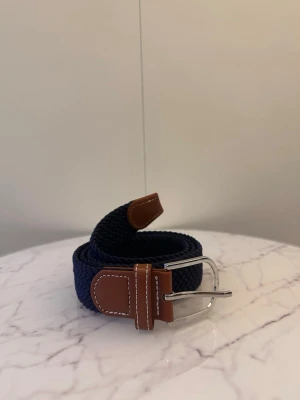 Mörkblå flätat bälte - Tja säljer helt nya svenska klassiska flätade bälten från Bältgallerian i storlek 105cm lång och 3,5cm bred. Dem är i ett elastiskt material och finns i flera olika färger i min profil
