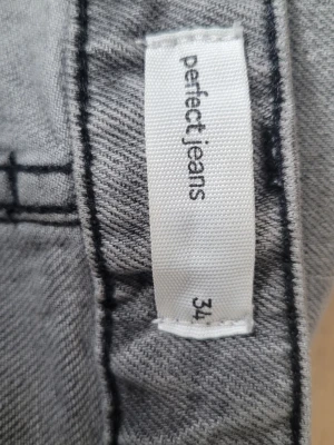 Gråa vida jeans från Perfect Jeans - Säljer ett par gråa jeans från Perfect Jeans i storlek 34. Jeansen har en rak och vid passform med klassiska bakfickor och snygga sömdetaljer. Perfekta för en avslappnad och trendig look.