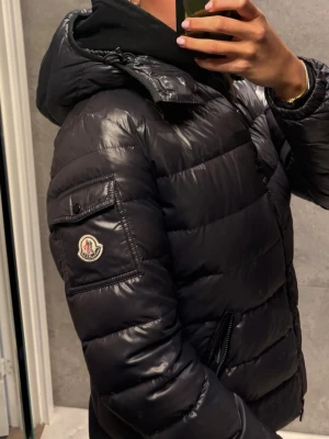  Moncler jacka model Bady  - Mörkblå Moncler Bady vinter jacka. Storlek 4 som passar storlek S något tight på mig jag är S/M. Passar M om du har mindre byst.   Jackan kom från vestiaire collective och då kom den utan cartoone.  Jackan har en defekt på armbågen se sista bilden. Pris kan diskuteras. 
