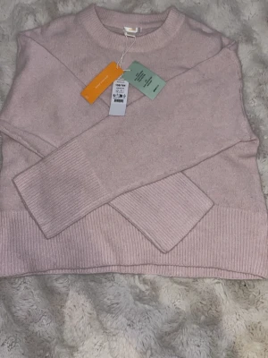 Ljusrosa stickad tröja från Gina Tricot - Supersnygg ljusrosa stickad tröja från Gina Tricot med rund halsringning och ribbade muddar vid ärmslut och nederkant. Tröjan har en enkel och clean design som passar perfekt till många olika looks. Materialet känns mjukt och skönt mot huden.