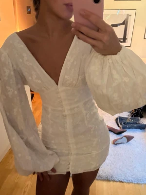 Adoore klänning vit - Adoore klänning, aldrig använd endast testad. Så fin till studenten. Vanligtvis bär jag S men denna i strl 34 sitter perfekt på mig. Klänningen sitter åt under bröstet men överallt annars sitter den löst och passar olika storlekar, nedan är mina mått för referens. Midja: 65cm Bröstkorg (under brösten): 75cm