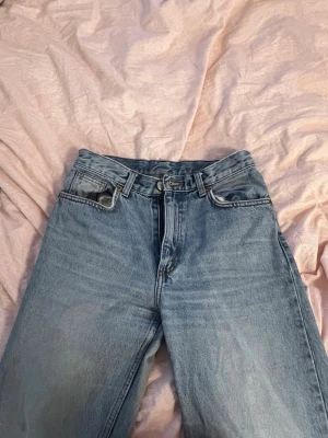 Ljusblå raka jeans från Monki - Säljer ett par ljusblå jeans från Monki med rak passform och klassisk femficksdesign. Jeansen har hög midja och är tillverkade i 100% bomull för en skön vintagekänsla. Perfekta till sneakers eller boots. Byxorna är baggy jeans