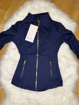 Mörkblå Nulu define jacket Lululemon i Stl.2 - Den lite mindre och smalare versionen av lululemons define jacket i Stl. 2 som motsvarar runt XS eller en riktigt tight S. Jag hade rekommenderat XS för bäst passform. Den är helt oanvänd och ren! 💞💞