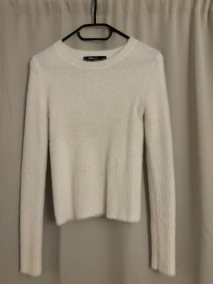Vit fluffig stickad tröja från new yorker  - Mysig vit stickad tröja med fluffig textur och rund halsringning. Tröjan har lång ärm och en passform som ger en trendig look. Perfekt att matcha med jeans eller kjol för en stilren outfit. Använd få gånger, köpt för 229kr 