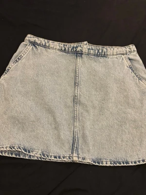 Ljusblå jeanskjol med dragkedja - Snygg ljusblå jeanskjol i kort modell med klassisk femficksdesign och dragkedja framtill. Perfekt till sneakers eller boots för en avslappnad look. Gjord i denim med en lätt A-linjeform.