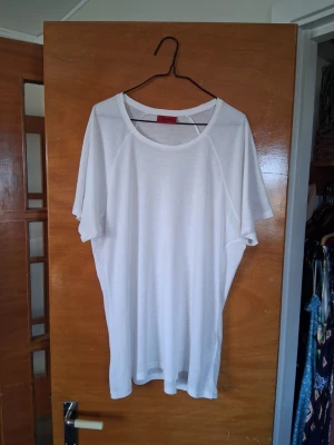 Vit t-shirt från Hugo Boss - Säljer en stilren vit t-shirt från Hugo Boss med klassisk rund halsringning och avslappnad passform. T-shirten är tillverkad i mjuk bomull och har korta ärmar. Perfekt basplagg för en clean och enkel look. 😃