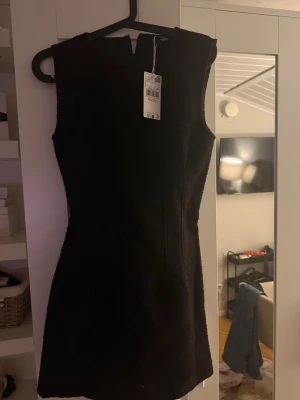 Svart ärmlös kort klänning  - Stilren svart ärmlös klänning från mango med figurnära passform och rund halsringning. Klänningen är kort och har en enkel, elegant design som passar perfekt till många tillfällen. Helt ny med prislapp. Köptes för 700 kr.