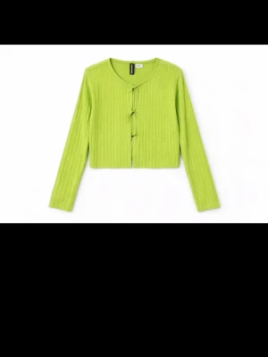 Grön ribbad kofta med knytning - Trendig ljusgrön ribbad kofta med långa ärmar. Croppad modell som ger en cool och modern look. Perfekt att styla över ett linne eller t-shirt för en extra pop av färg.