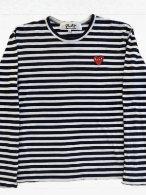 Randig långärmad topp Comme des Garçons - Snygg långärmad topp från Comme des Garçons Play med marinblå och vita ränder. Klassisk rund halsringning och ikoniskt rött hjärta med ögon broderat på bröstet. Perfekt för en trendig och avslappnad look.