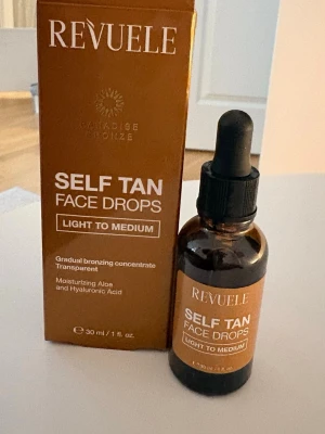 Revuele Self Tan Face Drops & Body Lotion - Säljer ett kit med Revuele Paradise Bronze Self Tan Face Drops (30 ml) och Self Tan Body Lotion (200 ml), båda i färgen Light to Medium. Face drops kommer i brun glasflaska med pipett och body lotion i bronsfärgad tub. Innehåller återfuktande aloe och hyaluronsyra.