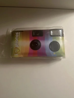 Engångskamera helt ny - Säljer en engångskamera från My Photos med Kameran har inbyggd blixt och klassisk plastdesign. Perfekt för att fånga ögonblick på film och enkel att använda. Kameran är kompakt och smidig att ta med sig överallt.