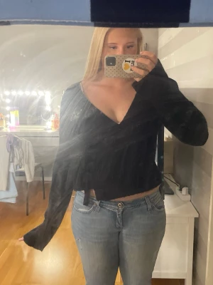 Svart omlott croppad topp - Säljer en svart croppad topp med omlott-design och v-ringning. Toppen har långa ärmar och är tillverkad i ett mjukt material som sitter skönt på kroppen. Perfekt för dig som gillar en stilren och enkel look.