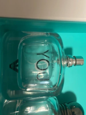 Stronger With You Intensely parfym tomma  - Stronger With You Intensely från Emporio Armani är en parfym i en elegant, genomskinlig glasflaska med rundade former och en silverfärgad metallkork. Flaskan har svart text och en modern, stilren design som känns lyxig och ungdomlig.