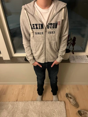 Grå zip-hoodie från Lexington - Tjenaret! Säljer nu en riktigt stilig zip hoodie från Lexington i storlek S! Mycket bra skick inga defekter, killen på bilden är ca 170 och den sitter bra på han. Hör av dig vid minsta fundering MVH Premium fashion 🤩