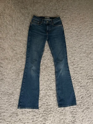 Blå bootcut jeans med lätt tvätt - Snygga blå bootcut jeans med klassisk femficksdesign och lätt tvättade detaljer på låren. Jeansen har normalhög midja.