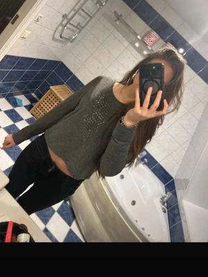 Grå croppad topp med nitar - Snygg grå topp med långa ärmar och fyrkantiga nitar i ett blixt mönster framtill. Mjuk och stretchig, perfekt till jeans eller kjol. Enkel rund halsringning och trendig passform. Nästan aldrig använd. Finns ingen lapp om storlek men uppskattar att det är S möjligtvis XS
