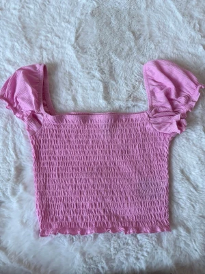 Rosa smockad topp med puffärmar - Supersöt rosa topp med smockat tyg  och korta puffärmar i storlek XS, nyskick.