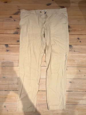 Beiga linnebyxor från Jack And Jones - Stilrena beiga chinos med raka ben och klassisk passform. Byxorna har knapp och dragkedja framtill samt två bakfickor med knapp. Tillverkade i ett lätt och bekvämt material som passar perfekt till en avslappnad look.