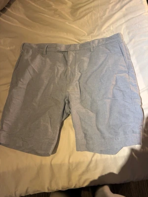 Ljusblåa shorts från Polo Ralph Lauren - Snygga ljusblåa shorts från Polo Ralph Lauren i klassisk modell med bälteshällor och sidofickor. Tillverkade i ett tunt och bekvämt bomullstyg, perfekta för sommardagar. Stängs med dragkedja och knapp framtill.