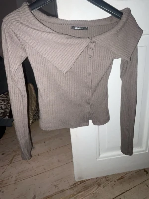 Ribbad brun kofta från Gina Tricot - Trendig ribbad kofta i brun nyans från Gina Tricot. Modellen har långa ärmar, bred krage och knäppning framtill. Perfekt för dig som gillar en stilren och enkel look med en twist. Materialet är mjukt och stretchigt för extra komfort. Använd endast en gång. 