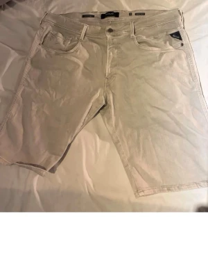 Beige denimshorts från Adidas - Säljer ett par beige denimshorts från Adidas med klassisk femficksdesign och knappstängning. Shortsens längd går ner till knäna och de har en avslappnad passform. Perfekta för dig som gillar en enkel och stilren look.