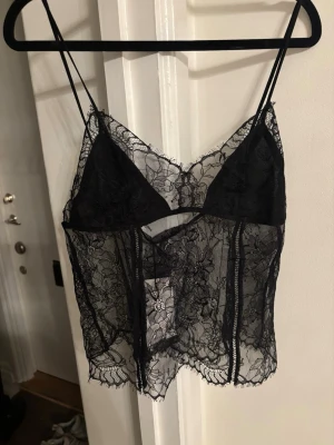 Svart spetslinne med tunna axelband helt ny från Zara - Snyggt svart linne i transparent spets med blommigt mönster och tunna axelband. Modellen har triangelformade kupor och en kort, lös passform. Perfekt för lager-på-lager eller som statement-piece. Materialet är mjuk och stretchig spets. Helt ny från Zara slutsåld överallt 💓