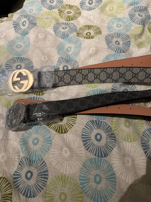  Bälte med monogramspänne - Två snygga bälten med klassiskt monogrammönster och stora spännen i guld och silver.  Helt ny, snabb affär=rabbat. Skriv för frågor. ST300. Båda 500