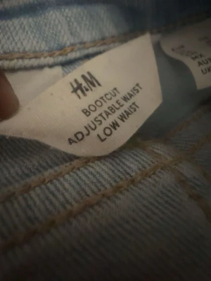 Bootcut jeans från H&M ljusblå - Säljer ett par ljusblå bootcut jeans från H&M med justerbar midja och låg midja. Jeansen har klassisk femficksdesign och är tillverkade i denim med snygg tvätt. Perfekta för dig. EUR 170