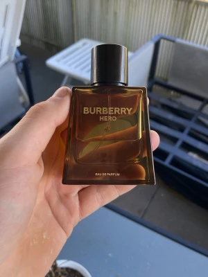 Burberry Hero Eau de Parfum - Burberry Hero Eau de Parfum i en stilren, fyrkantig glasflaska med mörkbrun toning och svart kork. Flaskan har en modern och maskulin design med tydlig Burberry-logga i silver. Perfekt för dig som gillar exklusiva dofter och snygg förpackning. Det är 25ml kvar i flaskan och pris kan diskuteras, ställ gärna frågor vid fundering!😇