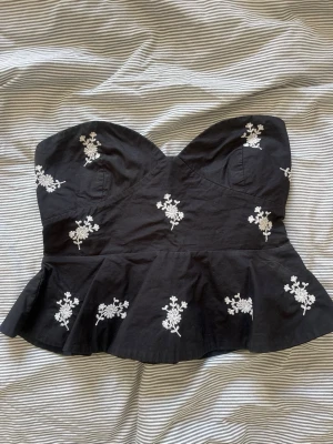 Svart axelbandslös topp med broderi - Supersnygg topp från Zara, säljer då den ej kommer till använing. Har tyvärr lite fläckar på baksidan men utöver det är den i toppskick!!💗