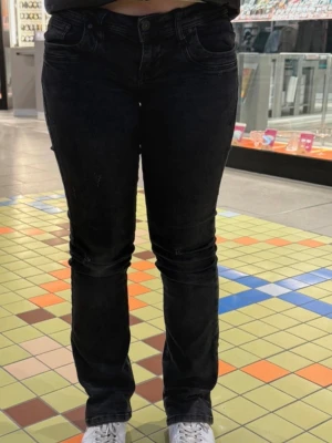 Lågmidjade jeans - Säljer ett par svarta jeans med bootcut passform och låg midja. Jeansen har klassiska fem fickor och subtila slitningar. Materialet är denim med stretch för extra komfort. Strl 25/30 valerie 