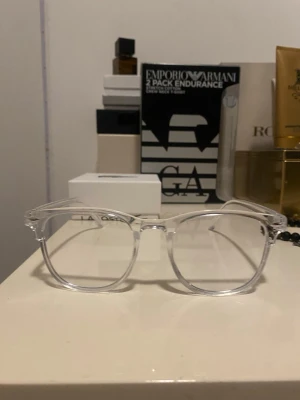 Transparenta glasögon med rund form - Snygga transparenta glasögon med rundad form och stilren design. Bågarna är helt genomskinliga och tillverkade i plast, vilket ger en modern och minimalistisk look. Perfekta som accessoar för att lyfta din outfit. Oanvända